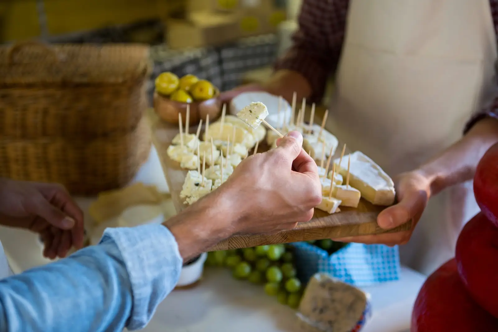 Staff showing a sample of cheese to customer at counter in market