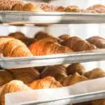 close up of golden croissants on baking trays at kitchen