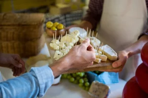 Staff showing a sample of cheese to customer at counter in market